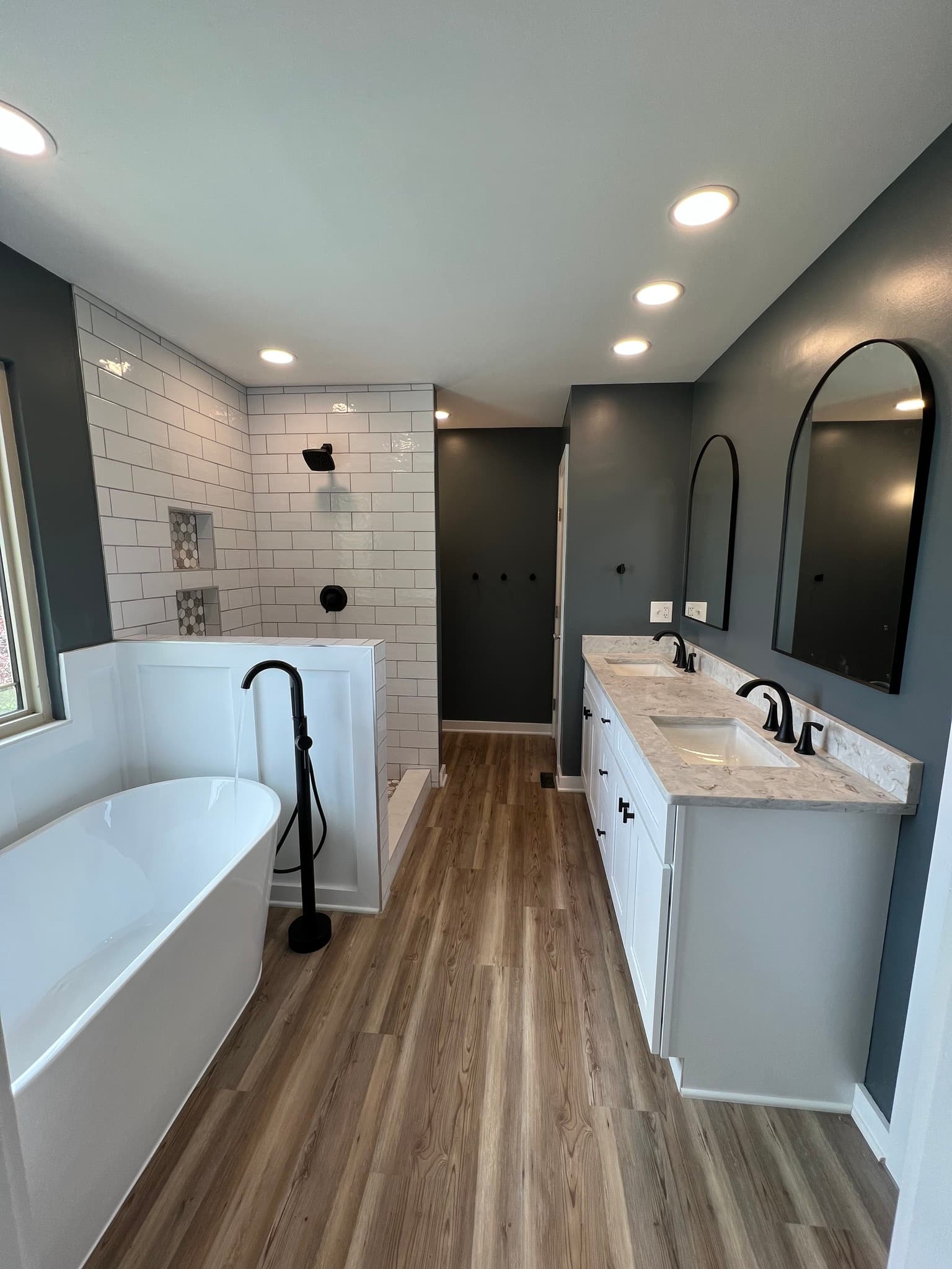 Modern farmhouse bathroom with a freestanding soaking tub, a white subway-tile shower, and a double vanity.